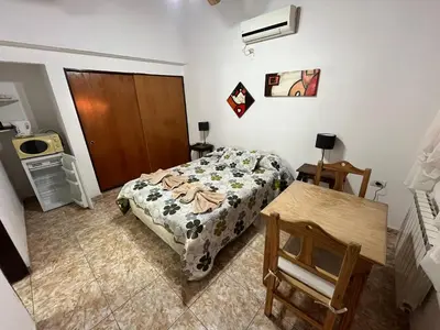 a small bedroom with a bed and a table at Complejo El Viejo Nogal in Villa General Belgrano