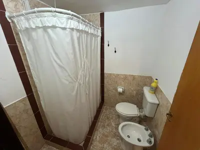 a bathroom with a white shower curtain and a toilet at Complejo El Viejo Nogal in Villa General Belgrano