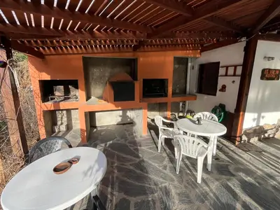 a patio with white tables and chairs and a fireplace at Complejo El Viejo Nogal in Villa General Belgrano