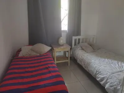a bedroom with two beds and a table and a window at dpto próximo patio olmos pileta in Cordoba