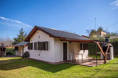a small white house with a table in the yard at Cabañas Montecarlo 2 in Santa Rosa de Calamuchita