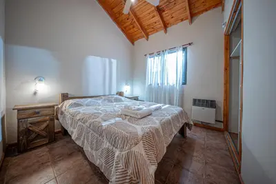 a bedroom with a bed with a blanket on it at Cabañas Montecarlo 2 in Santa Rosa de Calamuchita