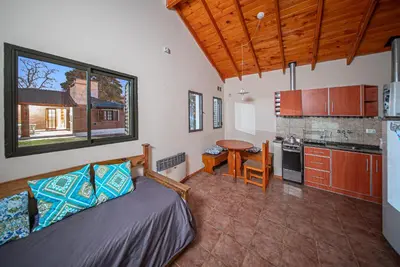 a room with a bed and a kitchen with a table at Cabañas Montecarlo 2 in Santa Rosa de Calamuchita