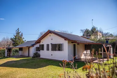 a white house with a pitched roof at Cabañas Montecarlo 2 in Santa Rosa de Calamuchita