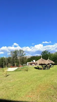 a field with a group of tables and straw umbrellas at Cabañas Vida Paz in Las Calles
