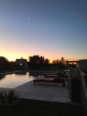 a bench sitting next to a swimming pool at sunset at Cabañas Vida Paz in Las Calles