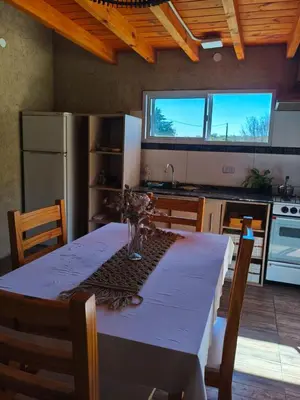 a kitchen with a table and a kitchen with a refrigerator at Cabañas Vida Paz in Las Calles