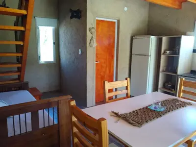 a dining room with a table and a refrigerator at Cabañas Vida Paz in Las Calles