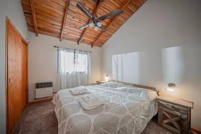 a bedroom with a large bed with a ceiling fan at Cabañas Montecarlo 3 in Santa Rosa de Calamuchita