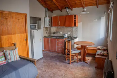 a kitchen with a table and a small kitchen with a table and chairs at Cabañas Montecarlo 3 in Santa Rosa de Calamuchita