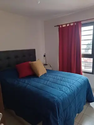 a bedroom with a blue bed with a red curtain at Departamento en zona Güemes in Cordoba