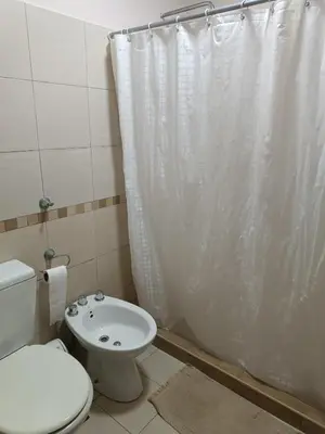 a bathroom with a toilet and a white shower curtain at Departamento en zona Güemes in Cordoba