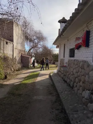 two people walking down a street next to a building at La loreta in Mina Clavero