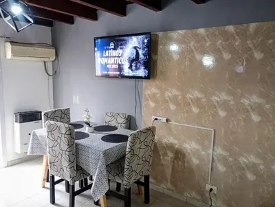 a dining room table with chairs and a tv on the wall at Departamento zanni in Cordoba