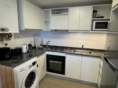 a kitchen with white cabinets and a washing machine at Rent a flat - Alto Paz Tower in Cordoba