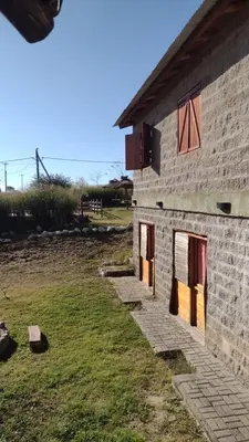 a brick building with red doors and a grass yard at El Alma De Yacanto Hotel Boutique in Villa Yacanto
