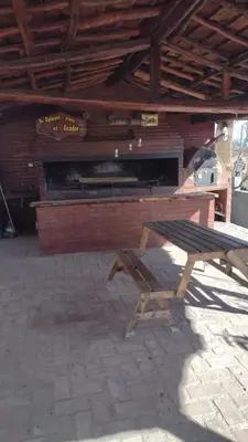 a picnic table and a bench in front of a fireplace at El Alma De Yacanto Hotel Boutique in Villa Yacanto