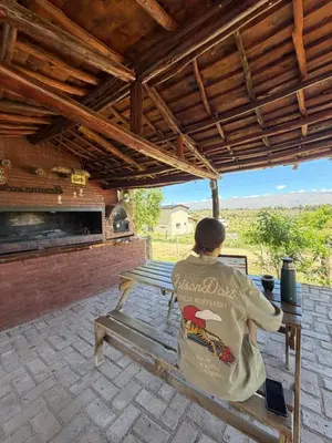 a woman sitting on a bench under a roof at El Alma De Yacanto Hotel Boutique in Villa Yacanto