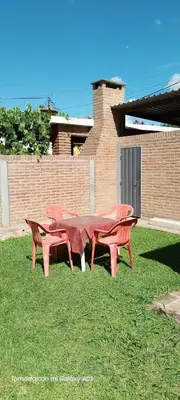 three red tables and benches sitting on the grass at Dpto Marina in Villa Cura Brochero