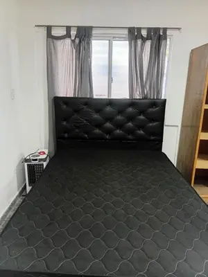 a black bed in a room with a window at Monoambiente Amoblado in Cordoba