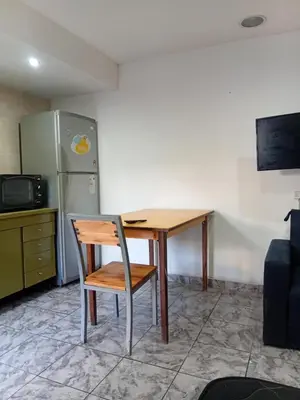 a wooden table with a chair and a refrigerator at Monoambiente Amoblado in Cordoba