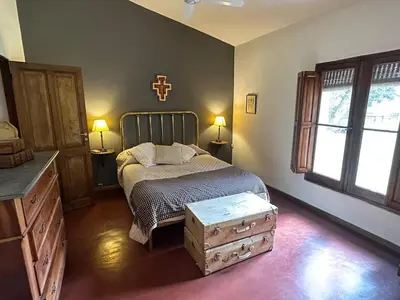 a bedroom with a bed with a dresser and two windows at Casa de campo con piscina, limpieza y desayuno in Río Cuarto
