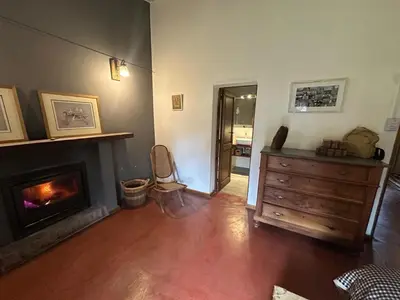 a living room with a fireplace and a wooden dresser at Casa de campo con piscina, limpieza y desayuno in Río Cuarto