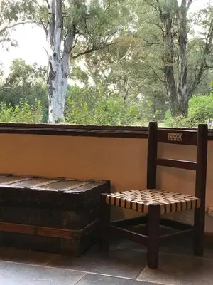 a bench and a chair in front of a window at Casa de campo con piscina, limpieza y desayuno in Río Cuarto
