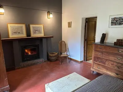 a living room with a fireplace and a dresser at Casa de campo con piscina, limpieza y desayuno in Río Cuarto