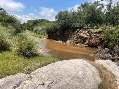 a river with a large rock in the foreground at Casa de campo con piscina, limpieza y desayuno in Río Cuarto