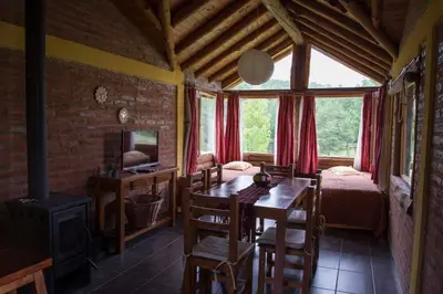a dining room with a table and a bed and a window at Cabañas Alma de Montaña