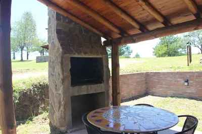 a patio with a table and a stone fireplace at Cabañas Alma de Montaña