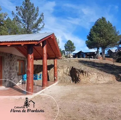 a house with a porch with blue chairs in front of it at Cabañas Alma de Montaña