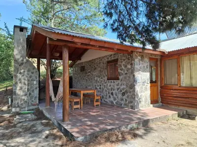 a stone house with a porch and a table at Cabañas Alma de Montaña