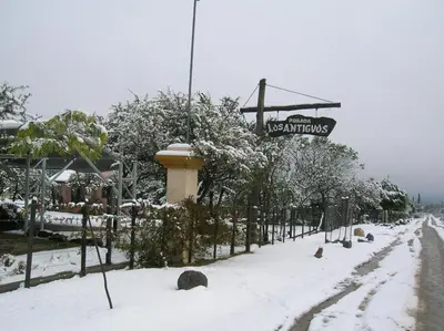 a snow covered street with a sign for a restaurant at Apart Los Antiguos in Merlo