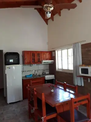 a kitchen with a wooden table and a white refrigerator at Complejo Lago Chico in Tanti