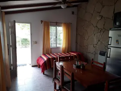 a dining room with a table and a bed at Complejo Lago Chico in Tanti