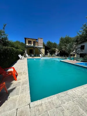 a swimming pool with a red chair next to a house at Santa Rosa Cabañas in Santa Rosa de Calamuchita