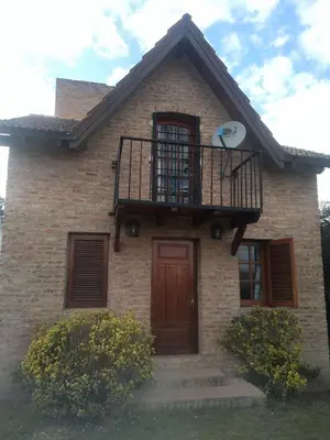 a brick house with a balcony on top of it at Los abuelos in Santa Rosa de Calamuchita