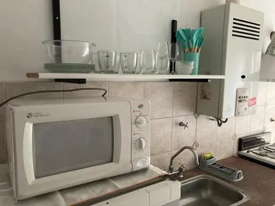 a microwave on a kitchen counter with glasses on shelves at Departamento Juniors in Cordoba