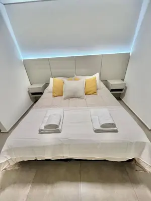 a bedroom with a large white bed with yellow pillows at Petit Premium Nueva Cba - Oulton in Cordoba