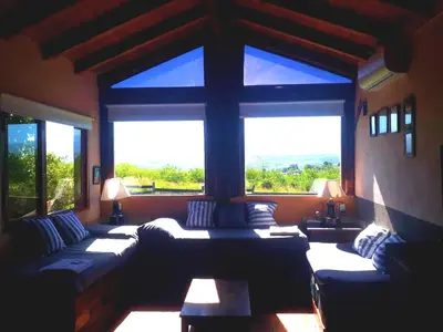 a living room with couches and a large window at Puesto Potrillos in Villa Yacanto