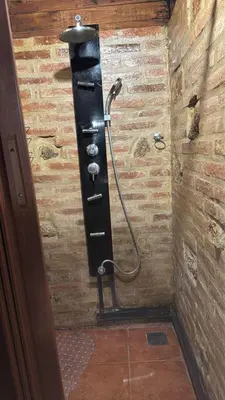 a shower with a hose attached to a brick wall at La casa de Pedro in San Roque