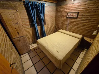 a small room with a bed and a blue curtain at Cabañas Eduviges in Mina Clavero