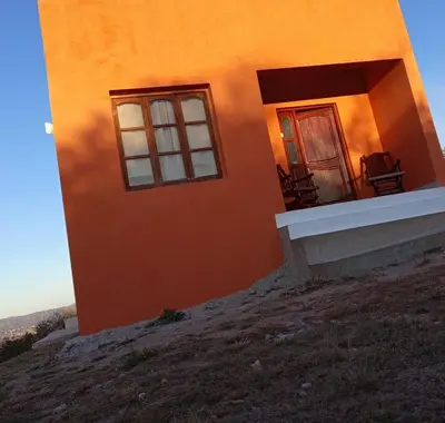 a house on a hill with two chairs in front of it at CABAÑA Casa Saavedra in Tanti