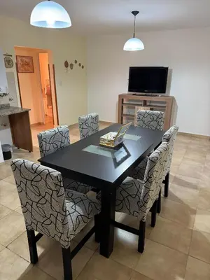 a dining room table with chairs and a television at Apart Dinkendein de 2 dormitorios in Río Cuarto