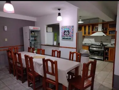 a kitchen with a table and chairs and a refrigerator at Carlos Paz Hostel Lodge in Villa Carlos Paz