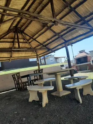 a picnic table and benches under a roof at Altos Aparts cabañas in Estancia Vieja