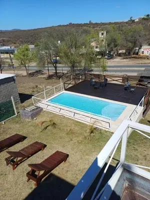 a swimming pool in a yard with two lounge chairs at Altos Aparts cabañas in Estancia Vieja