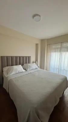 a bedroom with a large bed with white sheets and a window at Av Poeta Lugones - Nueva Córdoba in Cordoba